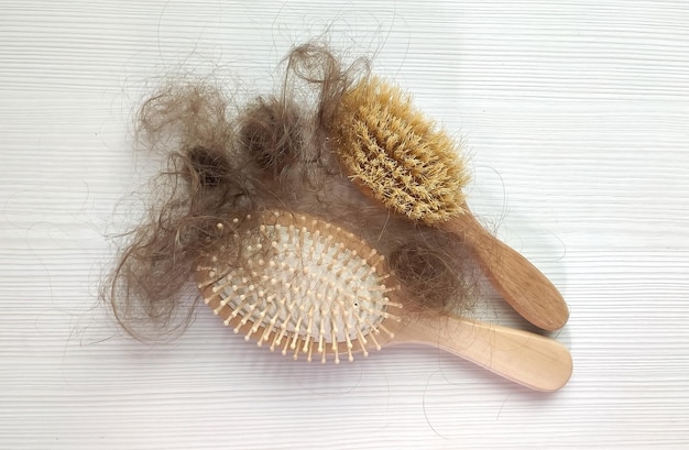 Primer plano de un cepillo con cabello perdido sobre una mesa de madera blanca