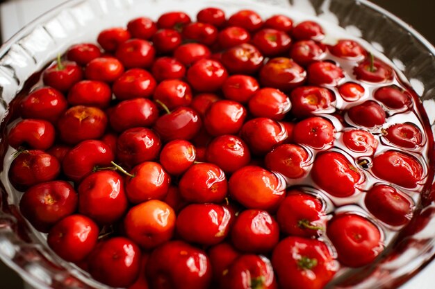 Foto primer plano de cerezas de acelora dentro de un cuenco de vidrio circular con agua