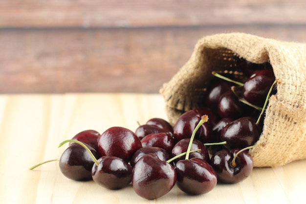 Primer plano de cerezas negras frescas sobre fondo de madera.