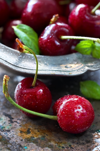 Primer plano de cerezas oscuras y hojas de menta fresca en un tazón pewt