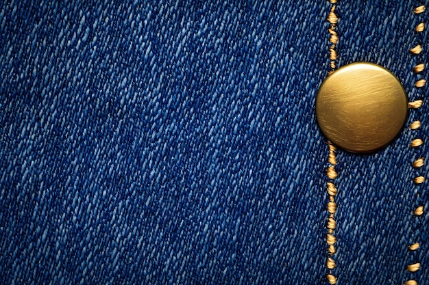 un primer plano de una chaqueta de jean azul con un botón dorado