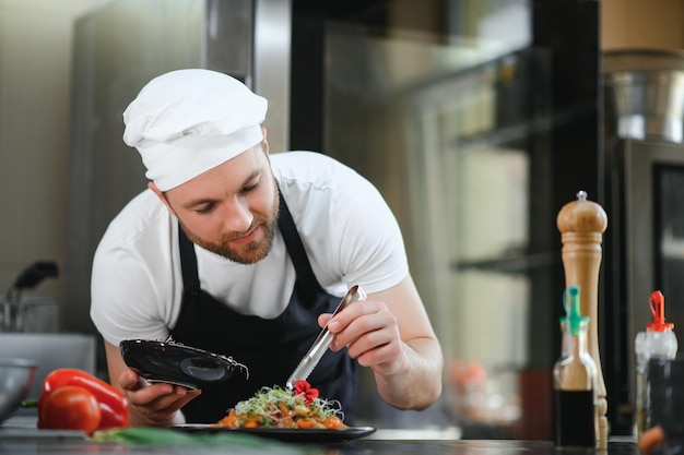 Primer plano de un chef masculino concentrado guarnición de alimentos en la cocina