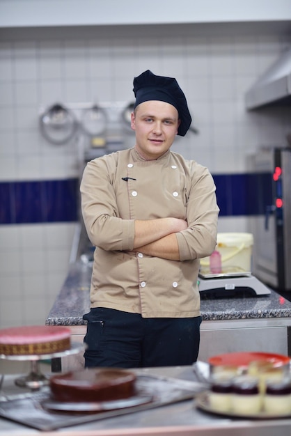 Primer plano de un chef de repostería masculino concentrado decorando comida de pastel de postre en la cocina