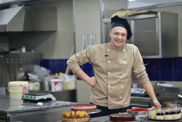 Primer plano de un chef de repostería masculino concentrado decorando comida de pastel de postre en la cocina