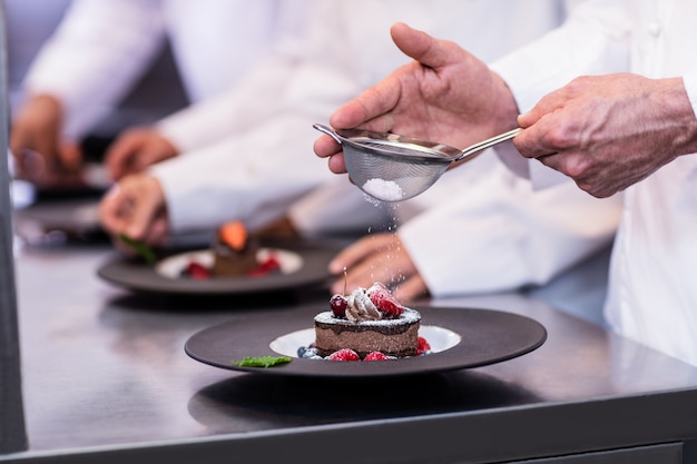 Foto primer plano del chef terminando un plato de postre