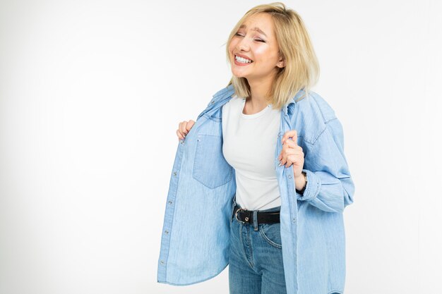 Primer plano de una chica atractiva sexy en una camisa de mezclilla azul y camiseta blanca posando sobre un fondo blanco de estudio