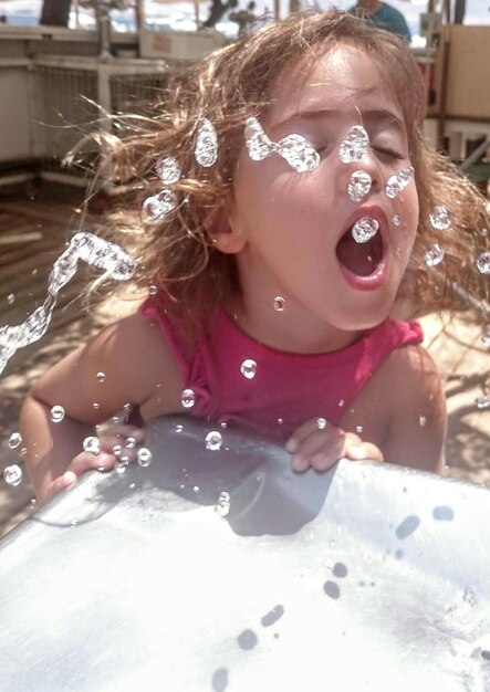 Foto primer plano de una chica bebiendo agua del grifo al aire libre.