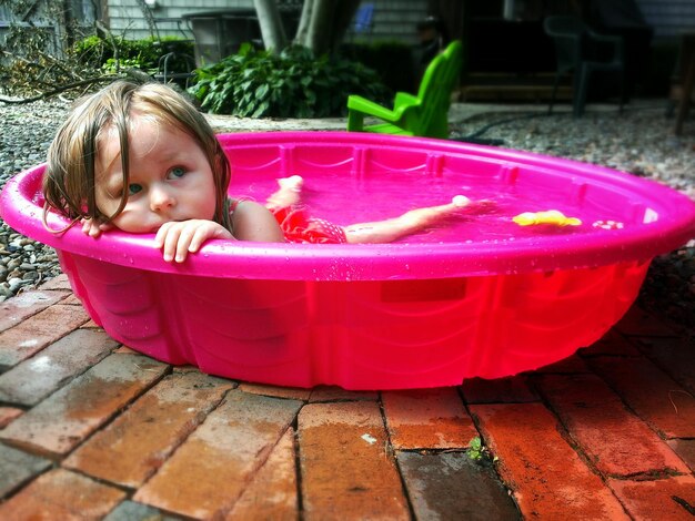 Primer plano de una chica linda en una bañera de agua rosa