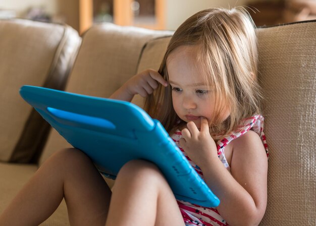 Primer plano de una chica linda usando una tableta digital en el sofá