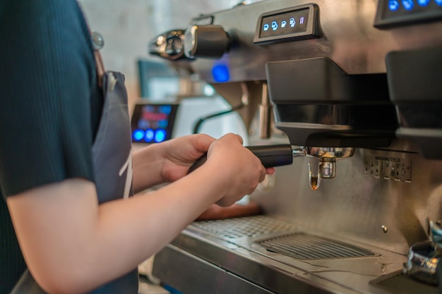 Primer plano chica mano sosteniendo un portafiltro con café de la mañana Camarero haciendo latte Preparación