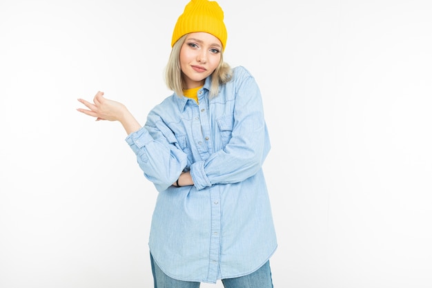 Primer plano de una chica modelo en una elegante camisa de mezclilla con un corte de pelo rubio sobre un fondo blanco de estudio.