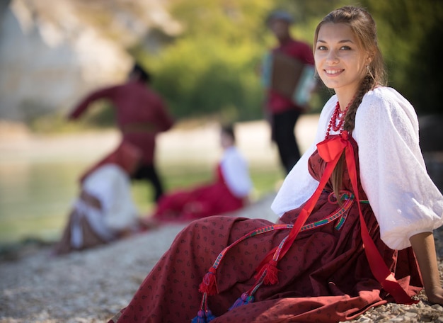 Foto en primer plano, una chica muy hermosa con un traje nacional se sienta y sonríe a la cámara, de cerca