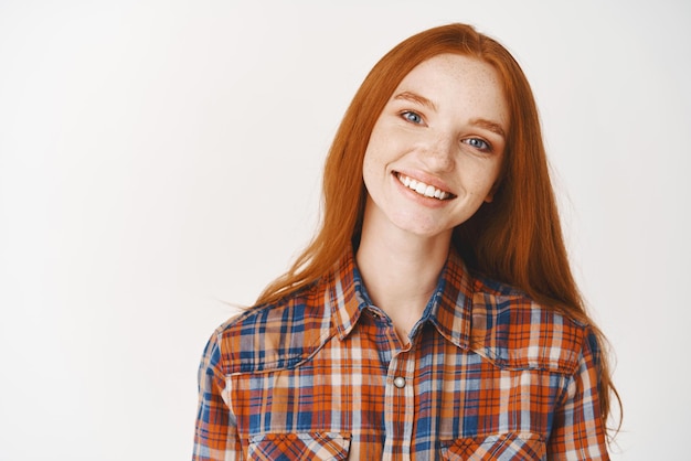 Primer plano de una chica pelirroja feliz sonriendo a la cámara de pie sobre fondo blanco Copiar espacio