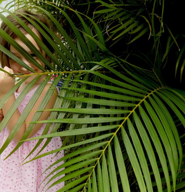 Foto primer plano de una chica de pie junto a una planta verde fresca