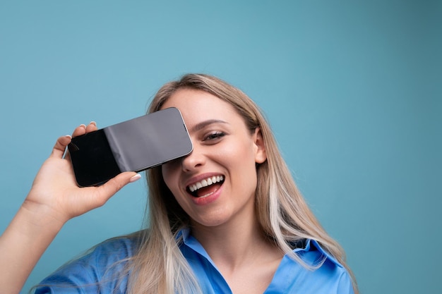 Primer plano de una chica rubia europea feliz sosteniendo una pantalla de teléfono inteligente con una maqueta para una aplicación