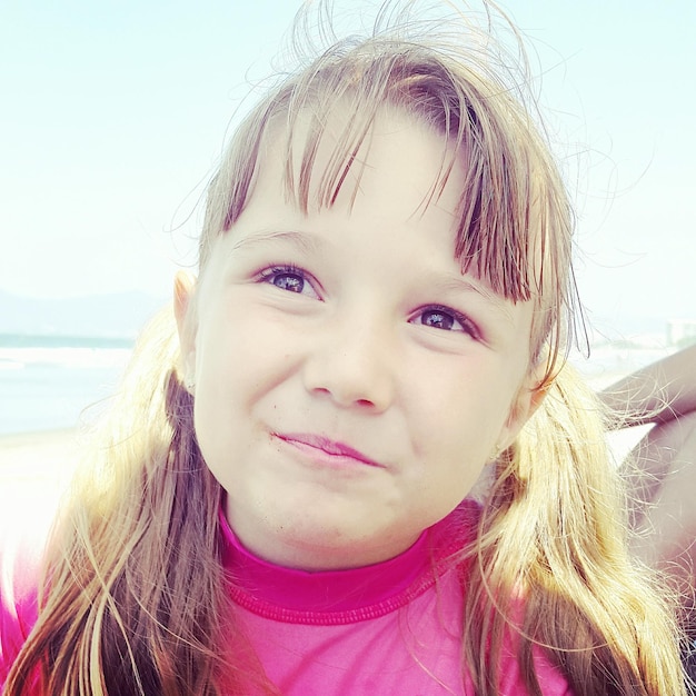 Primer plano de una chica sonriente mirando hacia la playa