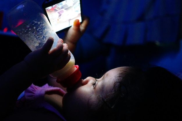 Primer plano de una chica usando un teléfono inteligente mientras bebe leche