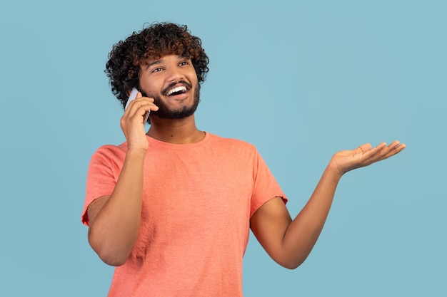 Primer plano de un chico indio feliz teniendo una conversación telefónica en azul