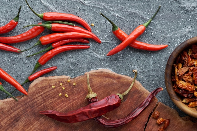 Primer plano de chiles rojos, frescos y secos, sobre madera y piedra gris