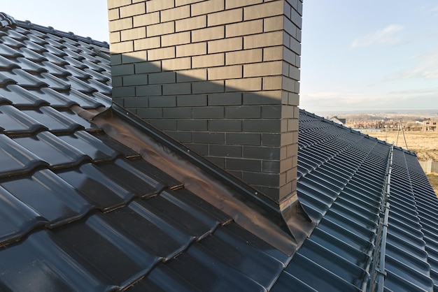 Primer plano de una chimenea de ladrillo en la azotea de la casa cubierta con tejas de cerámica Revestimiento de azulejos del edificio