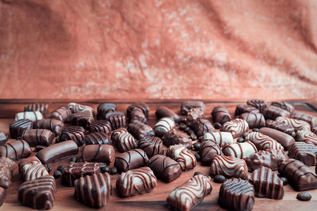 Primer plano de chocolates blancos y negros y granos tostados de café con fondo marrón