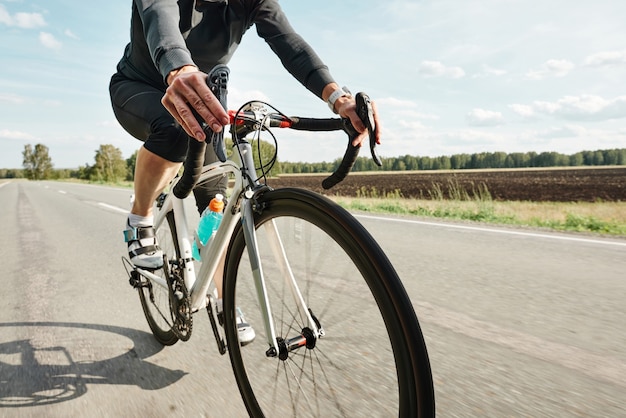 Primer plano de ciclista en ropa deportiva andar en bicicleta en una carretera rural
