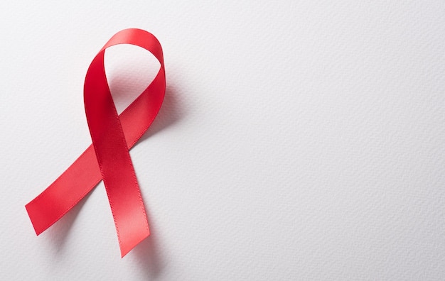 Primer plano cinta roja VIH día mundial del SIDA conciencia cinta sobre fondo blanco Concepto de salud y medicina