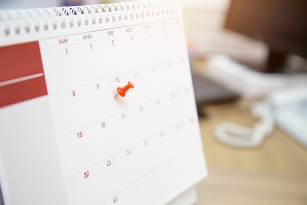 Primer plano de una clavija roja en el calendario de escritorio en blanco.