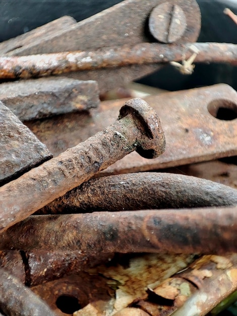 Primer plano de un clavo oxidado entre piezas de metal viejo