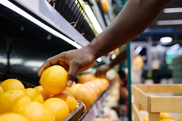 Primer plano de un cliente comprando naranjas frescas en el supermercado