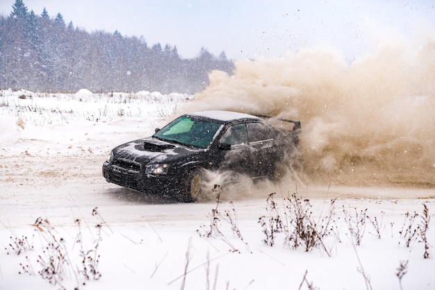 Primer plano de un coche a la deriva en invierno en la carretera cubierta de nieve