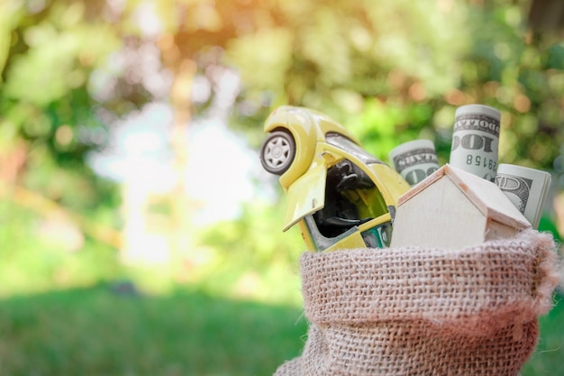 Foto primer plano de un coche de juguete con una casa modelo y dinero de papel en arpillera