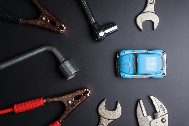 Foto primer plano de un coche de juguete con herramientas de trabajo sobre un fondo negro