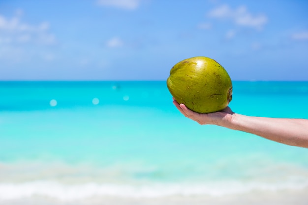 Primer plano de coco en manos masculinas contra el mar turquesa