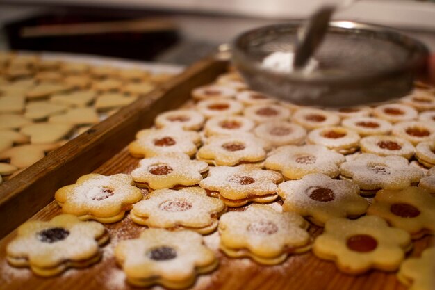 Primer plano de un colador rociando azúcar en polvo en las galletas en la mesa