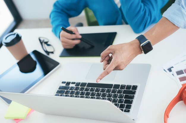 Primer plano de colegas de negocios usando la computadora portátil mientras trabajan en la oficina