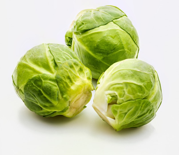 Primer plano de coles de Bruselas crudas, frescas y enteras (coles - Brassica oleracea). Aislado sobre fondo blanco