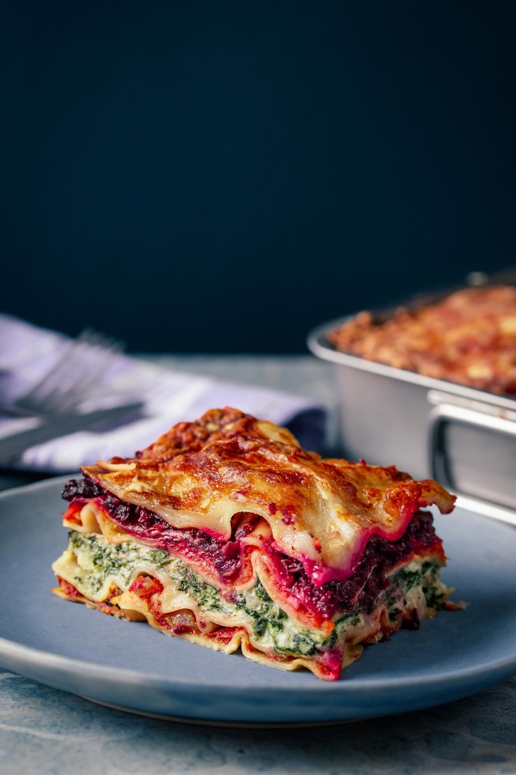 Foto un primer plano de las coloridas lasagna vegetariana de arco iris en un plato azul