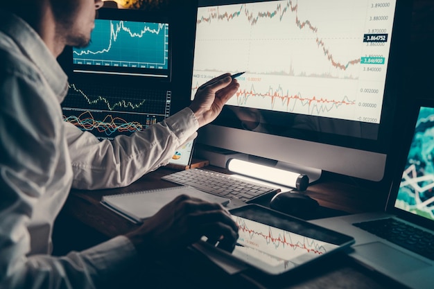 Foto primer plano de un comerciante masculino planeando una estrategia de negocio mientras apunta al monitor de la computadora en la oficina nocturna