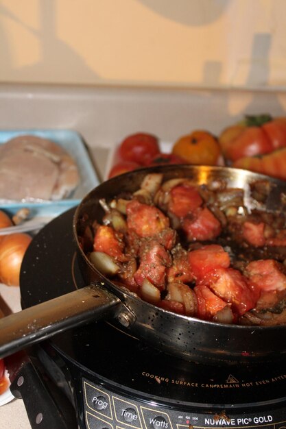 Foto primer plano de una comida con tomates, cebollas y pimientos en un mostrador con una pechuga de pollo cruda