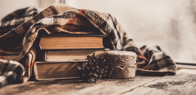 Foto primer plano de la composición en el alféizar libro con bufanda sobre fondo de madera.