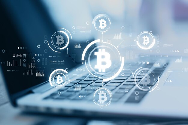 Primer plano de la computadora en un escritorio borroso con una interfaz de bitcoin azul brillante creativa en un fondo oscuro Tecnología financiera criptomoneda y concepto de intercambio Exposición doble