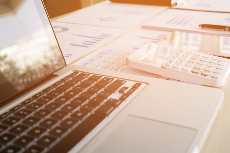 Primer plano de la computadora portátil, los documentos financieros y la calculadora en el escritorio de la oficina