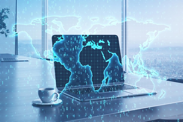 Primer plano de la computadora portátil en el escritorio con taza de café y holograma de mapa de código binario brillante sobre fondo borroso con ventana y vista de la ciudad Software y concepto de tecnología global Doble exposición