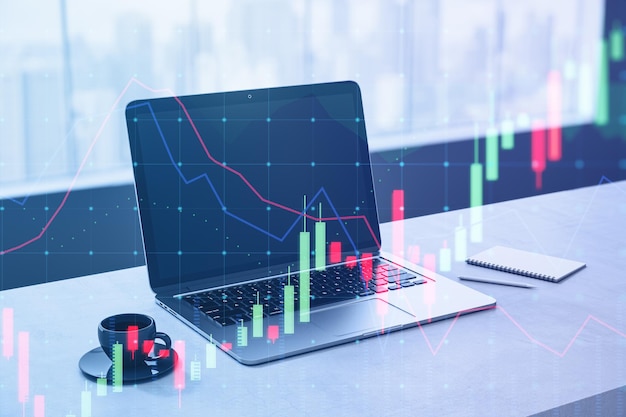 Primer plano de la computadora portátil en el escritorio con ventana de taza de café brillante con vista de la ciudad gráfico de divisas sobre fondo borroso Financiamiento comercial y concepto de inversión Doble exposición