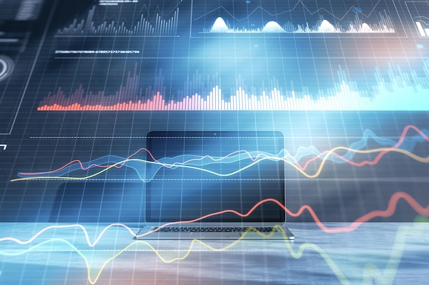 Primer plano de la computadora portátil con gráfico de negocios digital sobre fondo azul borroso Concepto de análisis y financiación comercial Doble exposición