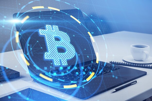 Primer plano de la computadora portátil con interfaz bitcoin redonda sobre fondo de escritorio borroso Concepto de criptomoneda y finanzas Doble exposición