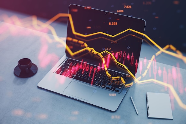 Primer plano de la computadora portátil en el lugar de trabajo con el bloc de notas de la taza de café y el gráfico de divisas en caída con índice sobre fondo borroso Crisis y concepto comercial en declive Doble exposición