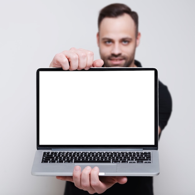 Foto primer plano de la computadora portátil con pantalla en blanco en manos del hombre sonriente