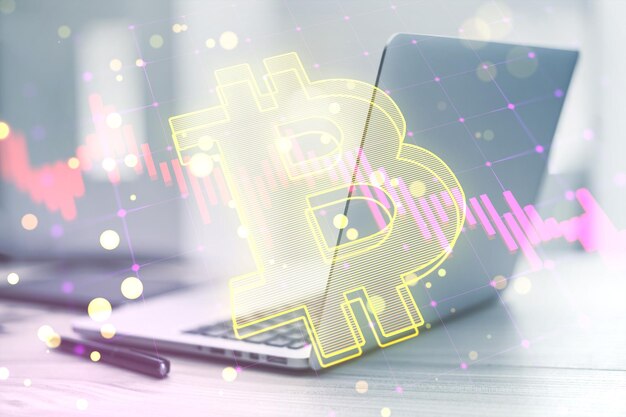 Primer plano de la computadora portátil y los suministros en el escritorio con la caída de la vela gráfico de divisas y bitcoin en fondo borroso concepto de criptografía y finanzas doble exposición